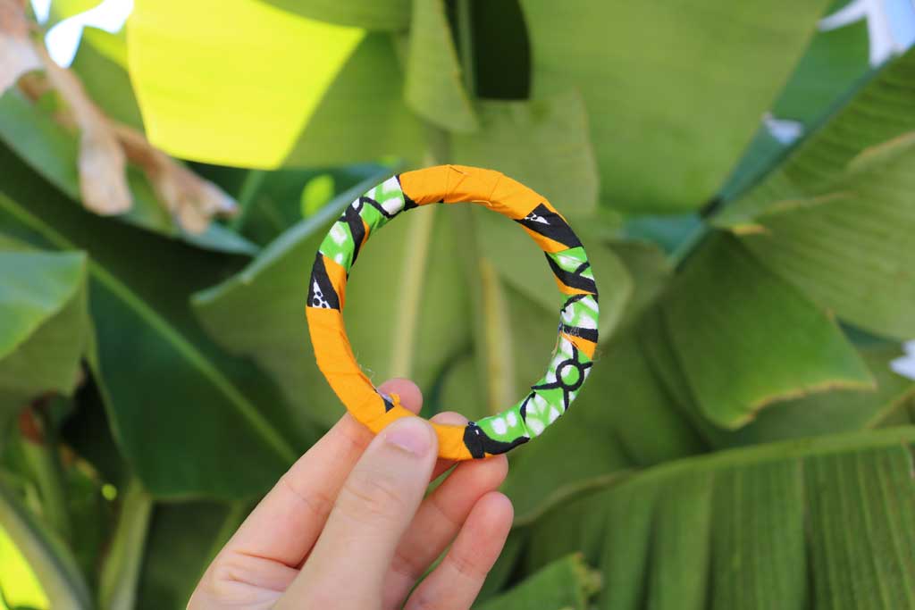 Uma mão a segurar a pulseira bangle azul com padrão africano
