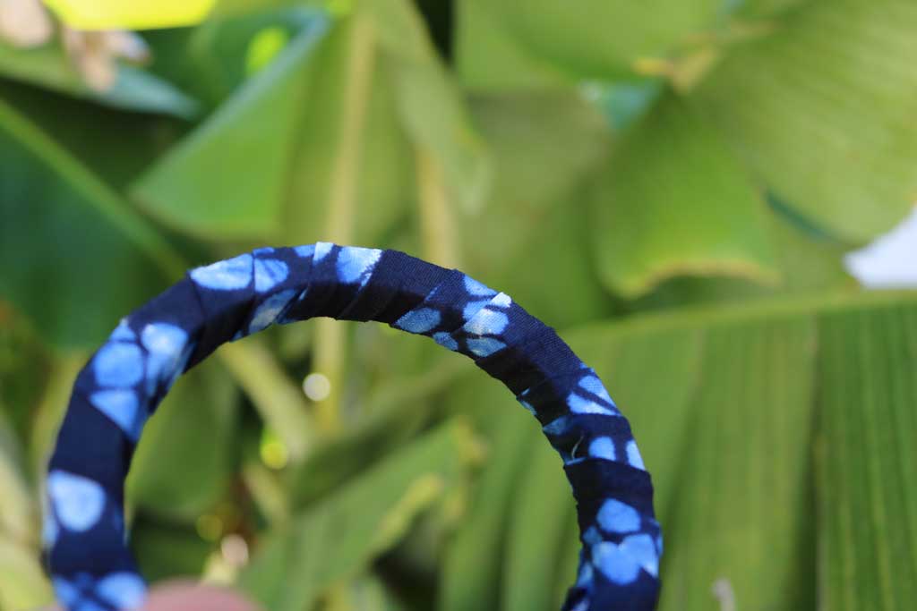 Pulseira artesanal azul com padrão africano sobre base rígida de madeira reaproveitada