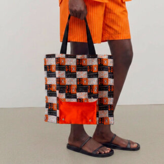 Uma modelo sostem o saco dobrável em tecido africano laranja