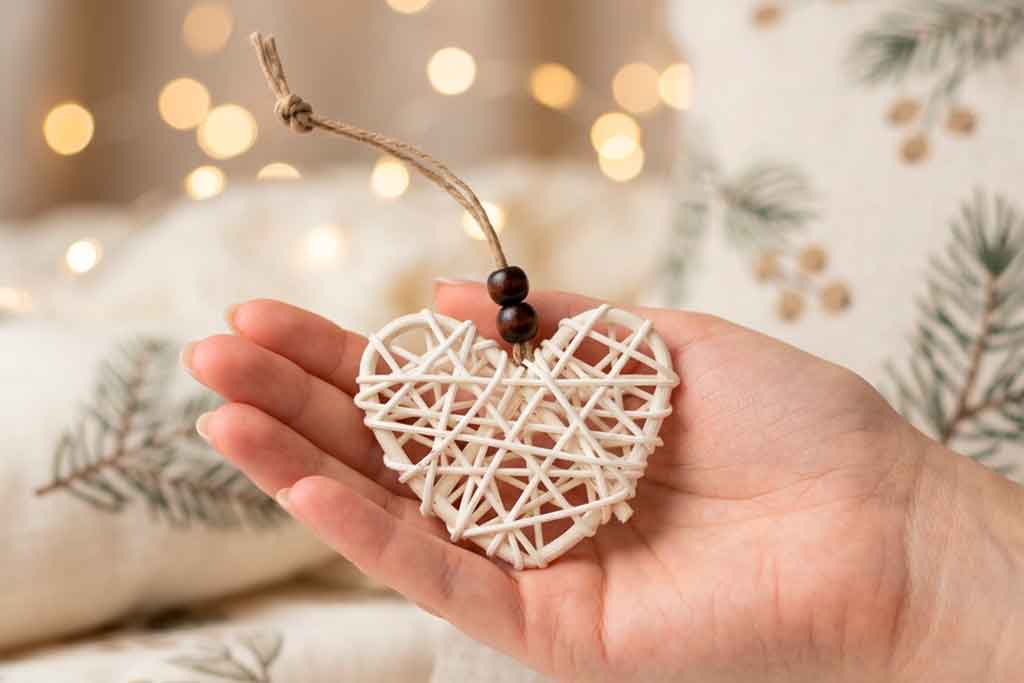 Enfeite de Natal em vime branco nas mão de uma mulher que assegura com gesto delicado