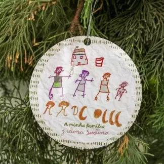 Enfeite de árvore de Natal feito em papel com desenho infantil de várias pessoas diante de uma casa